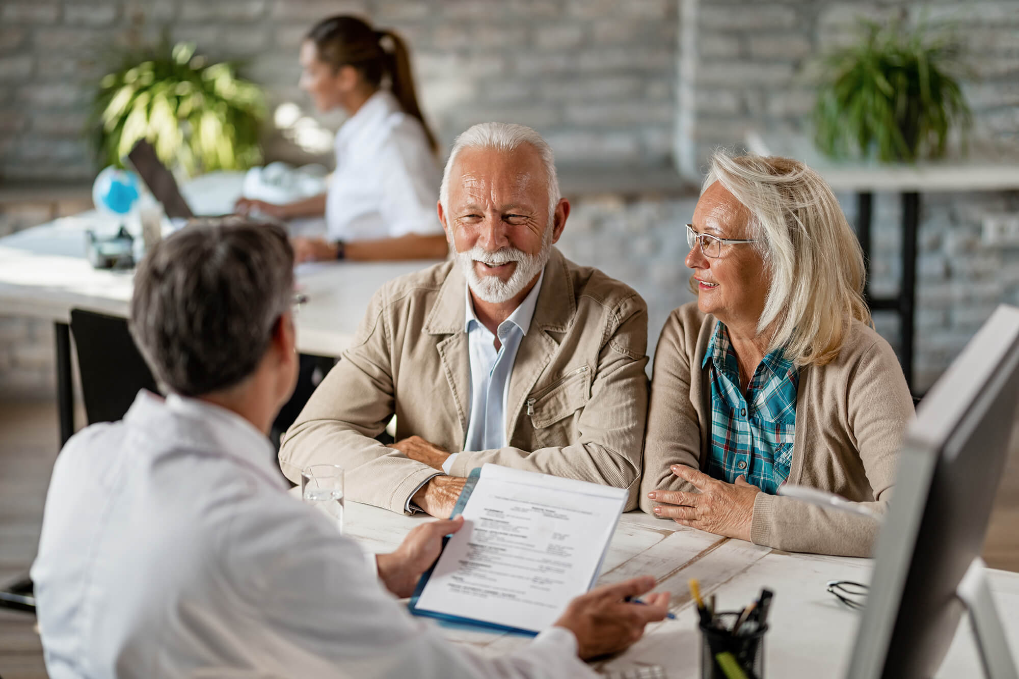 Mature couple talking to a doctor while going through their medical reports